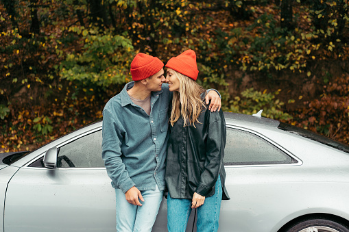 A young couple in love is embracing near the car. Valentine's day concept.