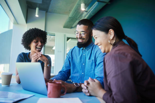 istock Diverse young businesspeople talking and laughing while working on a laptop 1454181116