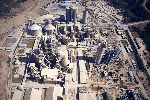 Huge cement producing plant. Aerial view of silos towers, pipes and other structures of industrial area