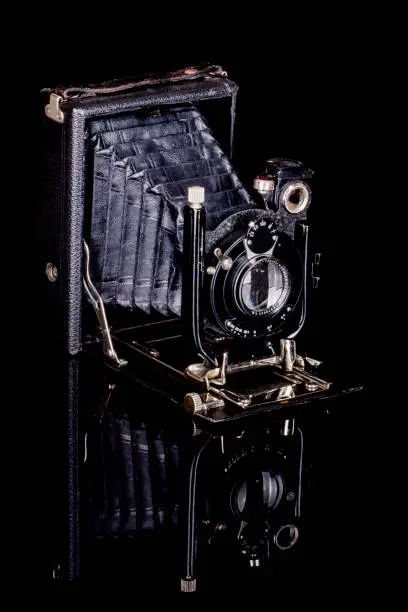 An old analogue plate camera from around 1920 is shown on a dark, reflective background.