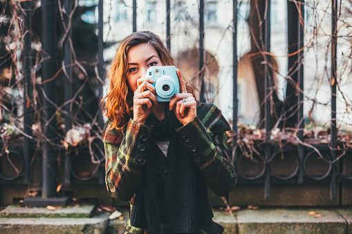 Young woman taking photos with polaroid camera