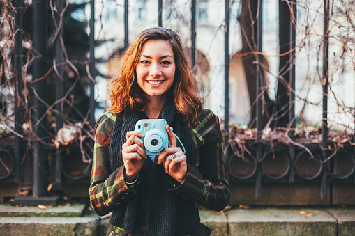Young woman taking photos with polaroid camera