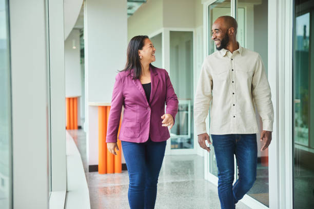 istock Diverse businesspeople talking and laughing while walking in an office hall 1454186384