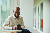 Businessman laughing at a text on his phone during break from work