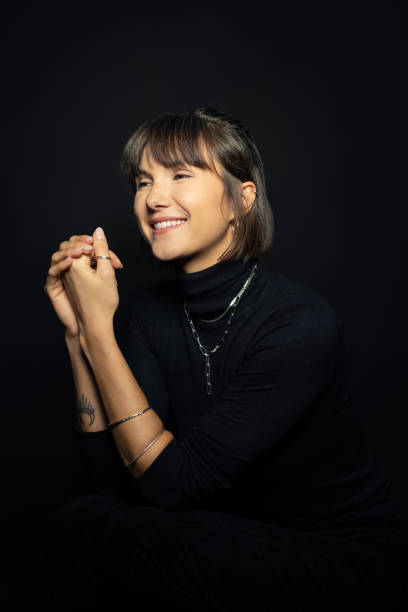 istock Smiling young woman sitting on black background 1454187855