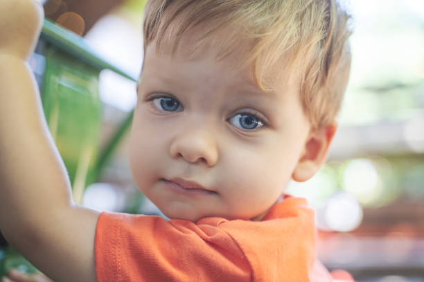 Baby boy looking at camera with blond, blue eyes stock photo