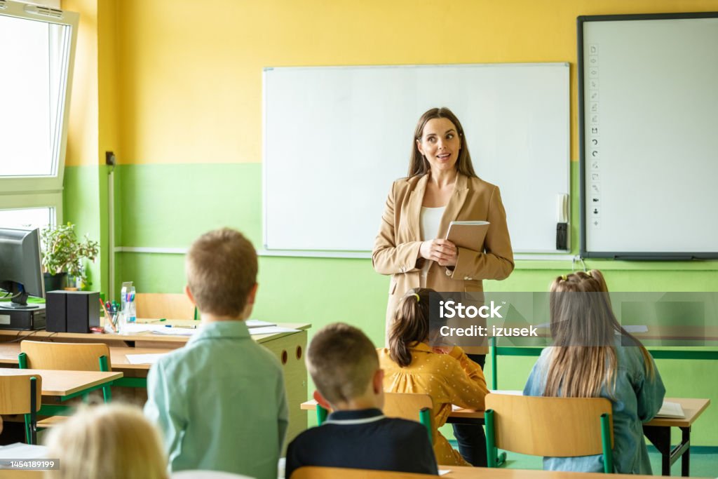 Female teacher and children in the classroom School children and female teacher during lesson in the classroom in the elementary school. 8-9 Years Stock Photo