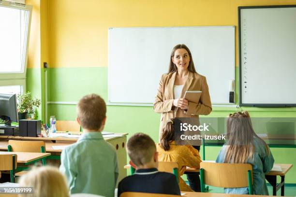 Female Teacher And Children In The Classroom Stock Photo - Download Image Now - 8-9 Years, Answering, Back to School