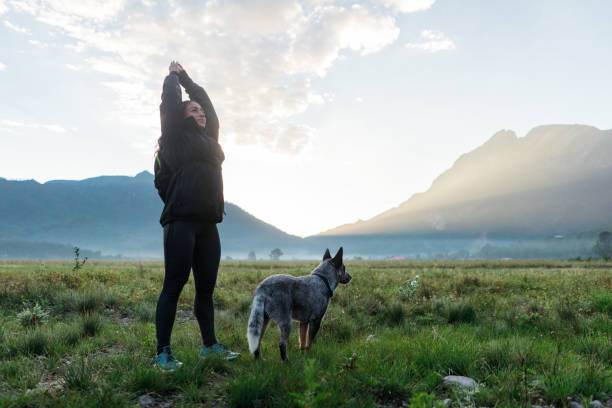 istock Young woman standing outdoors with dog and exercising 1454189379