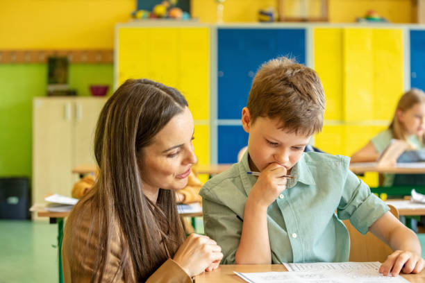 istock Female teacher helping boy during lesson 1454189384