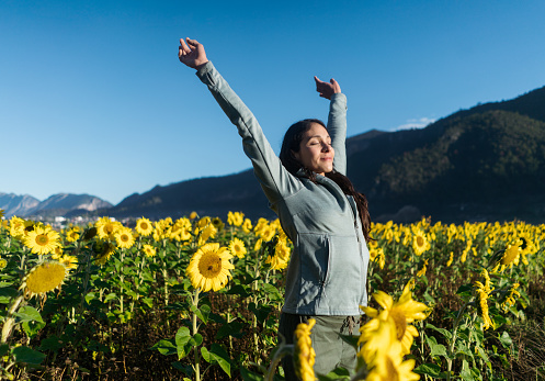 A young latin woman with her eyes closed standing in a sunflower field.