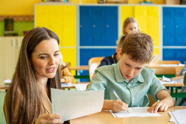 istock Female teacher helping boy during lesson 1454189595