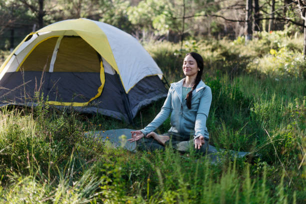 istock Young woman sitting on mat outside and meditating 1454189615