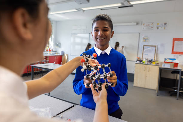 Helping a Friend in School A three-quarter length shot of a male and female teenager working together as a team to build a molecular structure. They are both wearing school uniforms. teenagers only teenager multi ethnic group student stock pictures, royalty-free photos & images