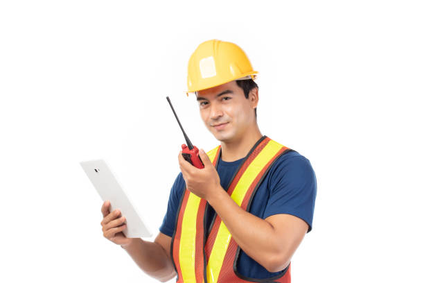 istock Construction handsome man worker in yellow helmet and reflective vest and using tablet for check work with team staff isolated on white background. 1454190019