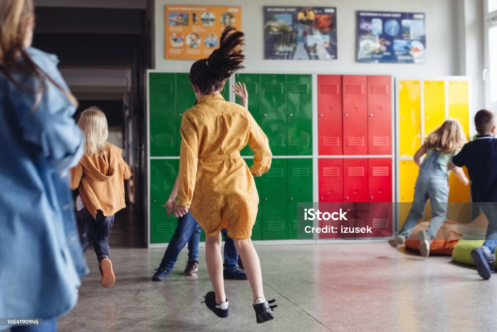 School kids running the school corridor Back view of happy girls and boys running in the school corridor. Back to School Stock Photo School kids running the school corridor Back view of happy girls and boys running in the school corridor. Back to School Stock Photo