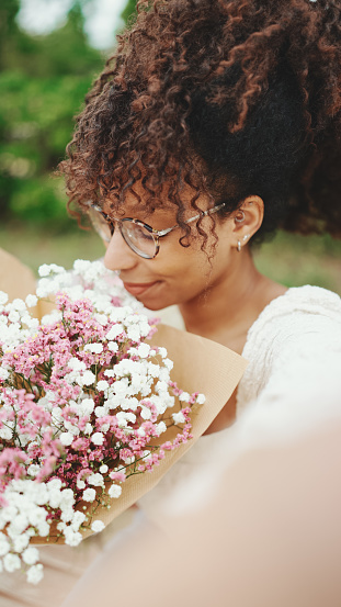 Young woman takes a selfie with a bouquet of flowers in the park on a bench. Girl takes a selfie with a flowers on mobile phone.