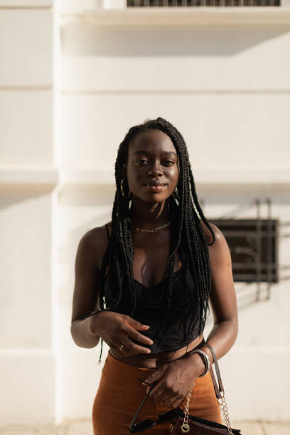 istock Young black female posing with style while holding her purse and looking at camera in the street 1454193334