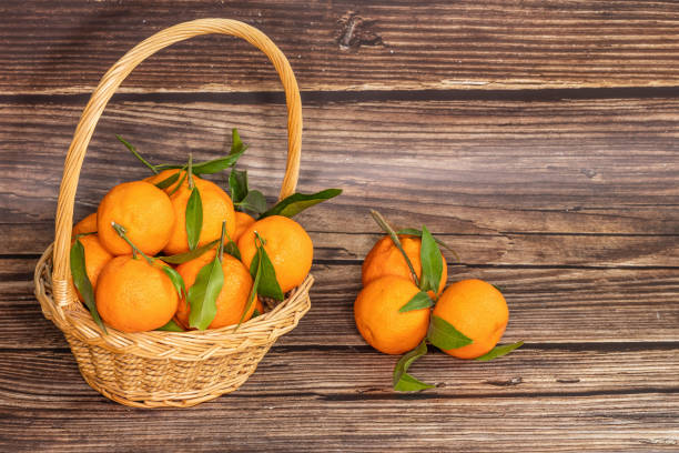 istock Tangerines in basket on wooden background. space for text 1454193543
