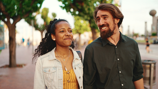 Closeup, man and woman walking smiling holding hands. Close-up of a young interracial couple in love going on a city street