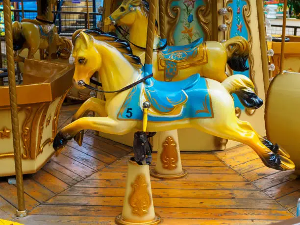 Photo of old carousel in the park with yellow horses