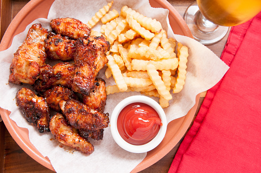 hot and spicy buffalo style chicken wings and fries in a basket