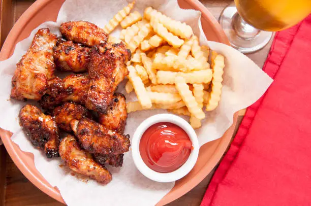 hot and spicy buffalo style chicken wings and fries in a basket