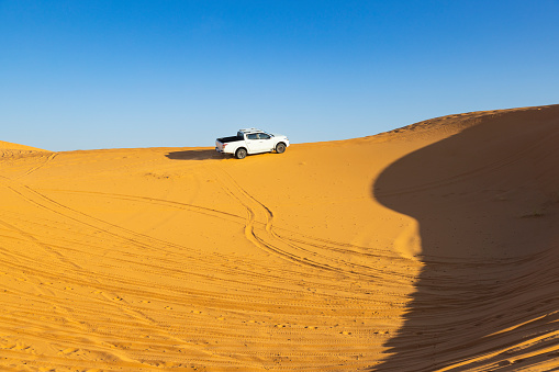 Car on sand dunes in the desert, Merzouga, Erg Chebbi sand dunes region, Sahara, Morocco.