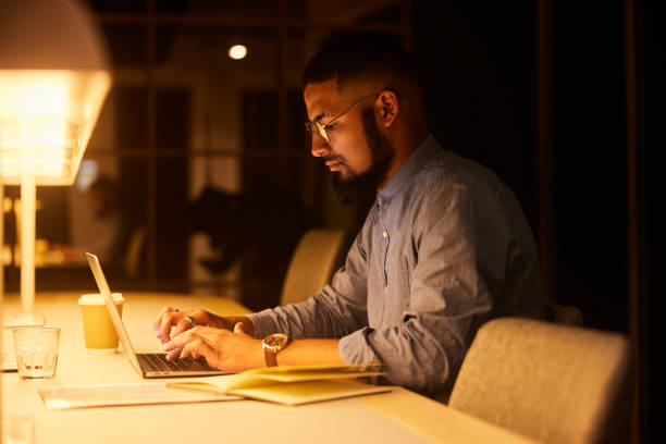 istock Young businessman using a laptop in an office at night 1454199051
