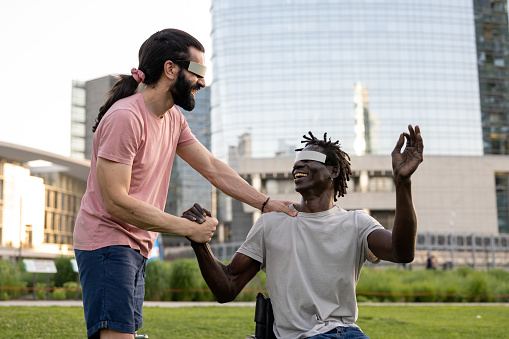 two friends using modern A.R. technology headsets, trying virtual reality outdoors, modern skyscrapers as background, futuristic lifestyle