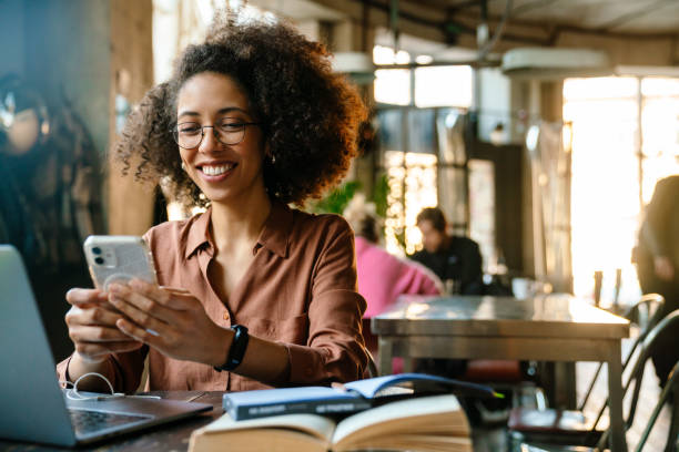 istock Young african american woman using cellphone while working in cafe 1454203039