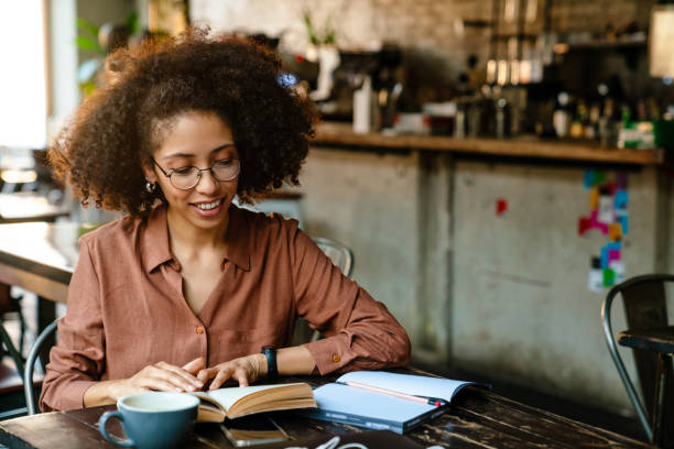 istock Young black woman making notes in planner book in cafe indoors 1454203465