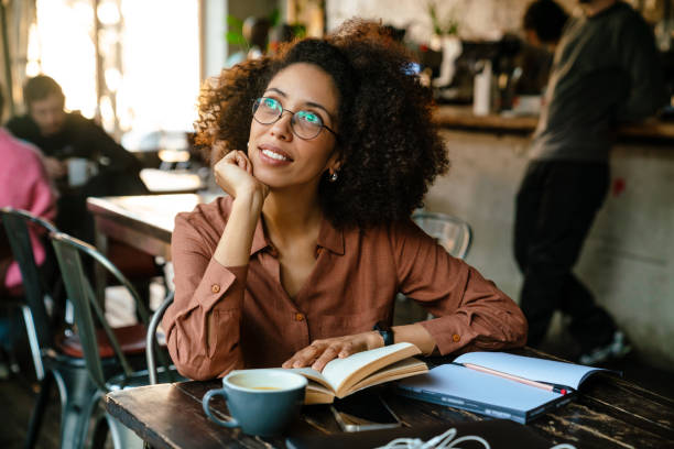 istock Young black woman making notes in planner book in cafe indoors 1454203506