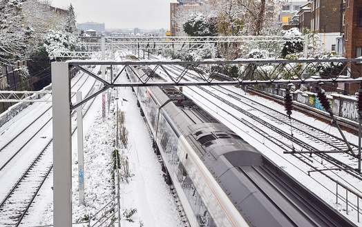 London, UK - December 12 2022: A train passes along snow-covered tracks