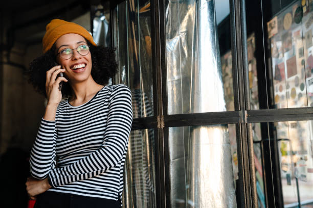 istock Young african woman smiling while talking on cellphone in cafe 1454204731