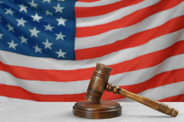 istock Wooden gavel on light grey table against American flag. Space for text 1454205776