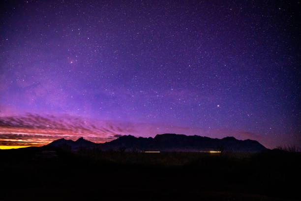 Sunlight and Car Lights Below Night Sky and Chisos Mountain Range in Big Bend National Park