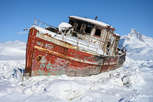 An old shipwreck at the frozen Tasiilaq Fjord, located in East Greenland.