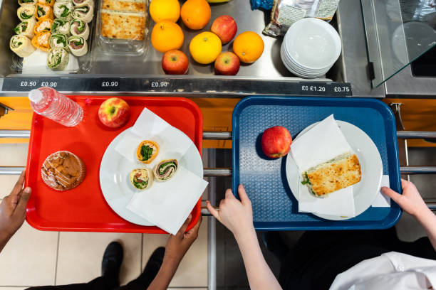 Having. A Light Snack An aerial view of two high school students with snacks for lunch out their trains in the school cafeteria in the school they go to in the North East of England. On display in the chiller fridge is lots of fruit and healthy options for lunch. cafeteria sandwich food healthy eating stock pictures, royalty-free photos & images