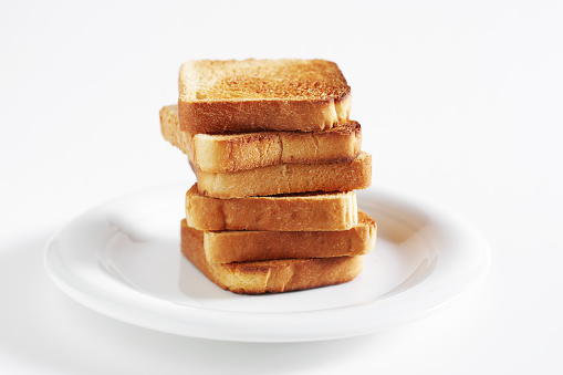Slices of small toasted bread on a plate on white background