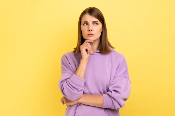 istock Thoughtful woman standing holding chin, looking away, thinks about something important. 1454208208