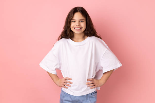 istock Delighted smiling little girl standing hands on hips, looking at camera with happy expression. 1454208288