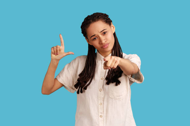 istock Serious woman with dreadlocks showing loser gesture and pointing at camera, accusing for failure. 1454209192