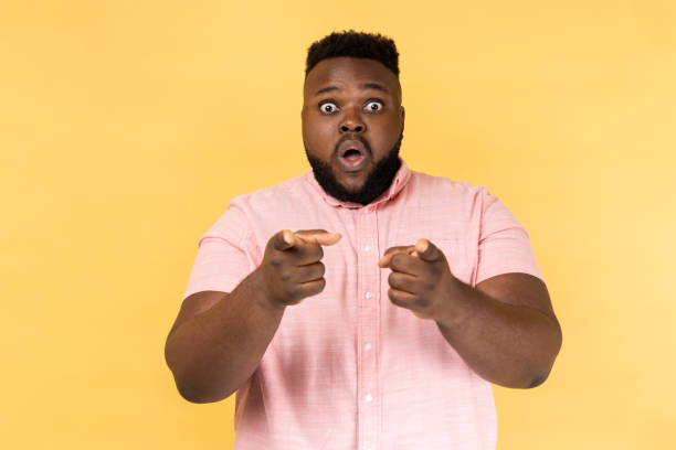 istock Man with open mouth pointing to you, making choice and expressing astonishment. 1454209299