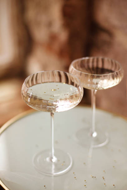 Glasses of champagne with glitter High angle of glass goblets of champagne with glitter placed on tray during event crystal chalice stock pictures, royalty-free photos & images