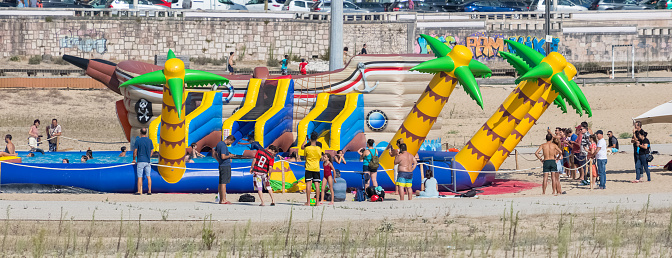 Figueira da Foz Portugal 08 09 2022: View of a mega inflatable, shape of palm trees, children's pool, located on the beach, families with their children playing, Figueira da Foz, Claridade beach