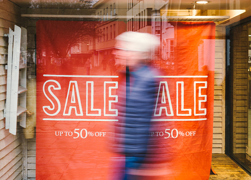 Sale sign in a store window advertising savings and discounts.