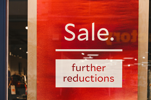Sale sign in a store window advertising savings and discounts.