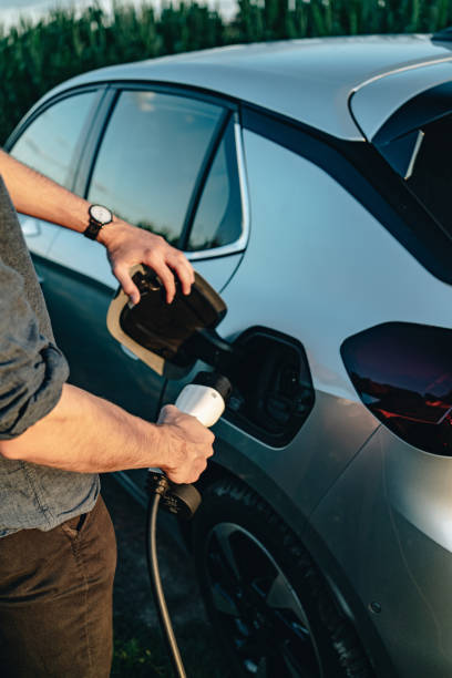 Young man recharges electric vehicle