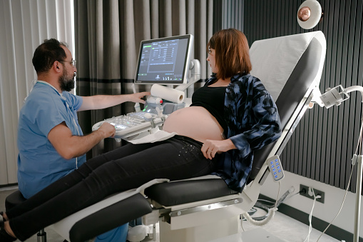 Pregnant woman watching ultrasound in gynecology clinic